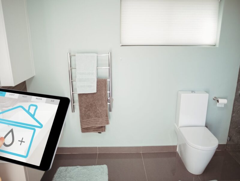 Digital composite of Hand using smart home application on digital tablet in washroom